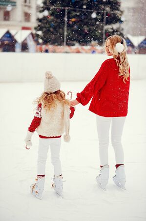 Family in a winter park. Mother with daughter in a ice arenaの写真素材