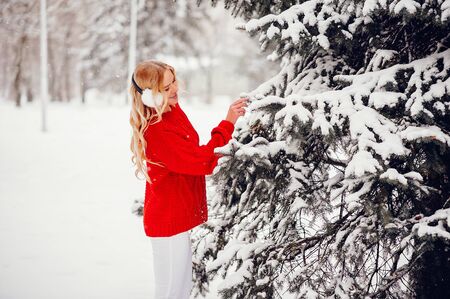 Cute girl walking in a winter park. Woman in a red sweaterの写真素材