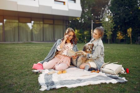 Girls sitting on a blanket in a summer parkの写真素材
