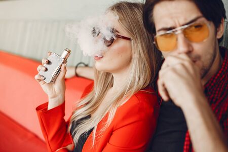 Stylish young couple with vape in a cityの写真素材