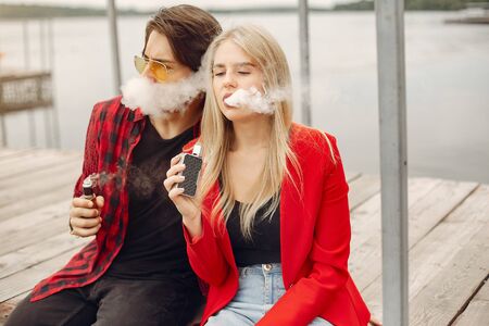 Stylish young couple with vape in a cityの写真素材