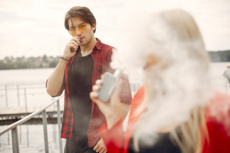 Stylish young couple with vape in a city
