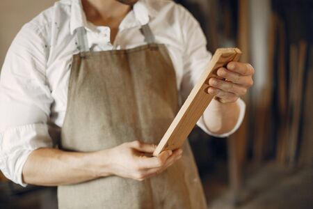 Man working with a wood. Carpenter in a white shirtの写真素材