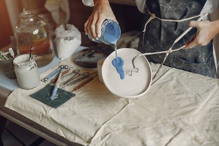 Woman in a pottery. Master make a dishes. Artist works with a clayの写真素材