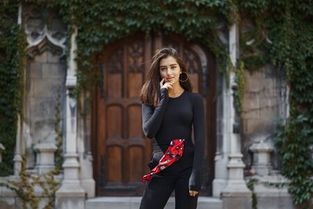 stylish brunette standing next to the entance to a buildingの写真素材