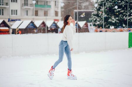 Cute and beautiful girl in a white sweater in a winter cityの写真素材