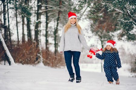 Little girl with mother playing in a winter parkの写真素材