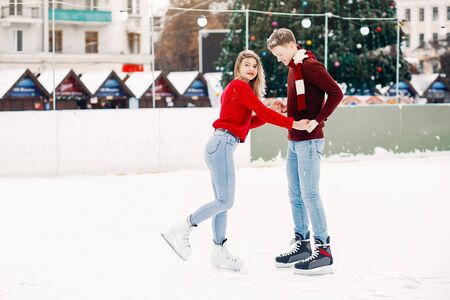 Cute couple in a red sweaters having fun in a ice arenaの写真素材