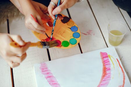 Beautiful little girl painting. Mother drawing with two girl. Family in a studioの写真素材