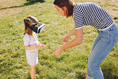 Family in a summer park. Mother with children. Cute little girl in a vr glasses
