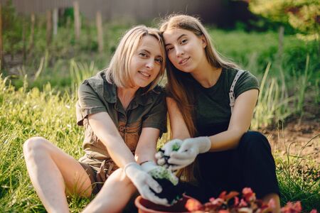 Mother with a daughter works in a garden near the houseの写真素材