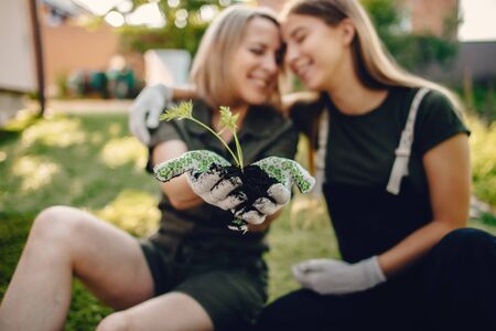 Mother with a daughter works in a garden near the houseの写真素材