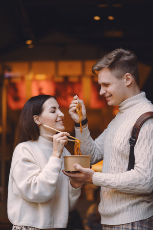newlywed couple eating noodles with chopsticks in Shanghai outside a food market