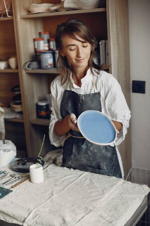 A young woman makes dishes in a potteryの写真素材