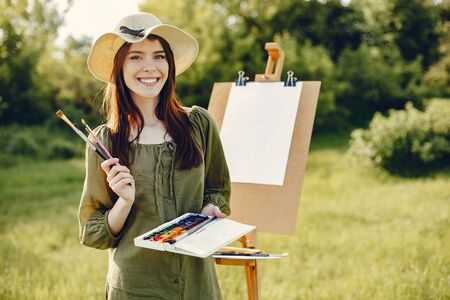 Elegant and beautiful girl painting in a fieldの写真素材