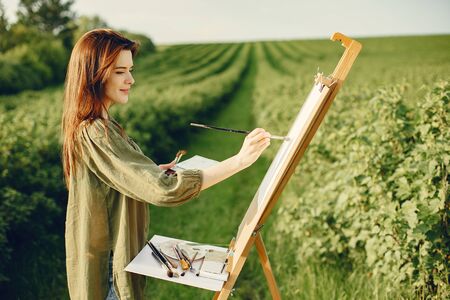 Elegant and beautiful girl painting in a fieldの写真素材