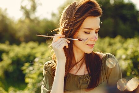 Elegant and beautiful girl painting in a fieldの写真素材