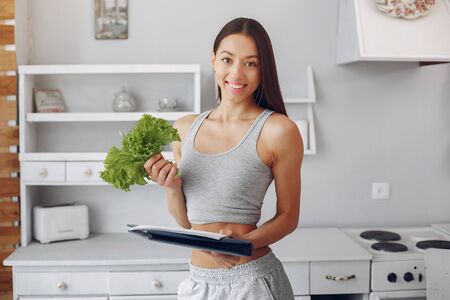 Beautiful and sporty girl in a kitchen with a vegetablesの写真素材