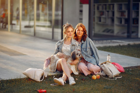 Two girls wallking in a park with a little dog