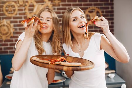 Cute friends in a cafe eatting a pizzaの写真素材