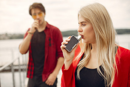 Stylish young couple with vape in a city