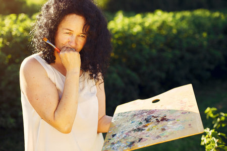 Beautiful adult woman drawing in a summer field