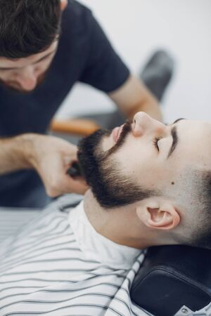 Man with a beard. Hairdresser with a client. Brunette in a barbershopの写真素材