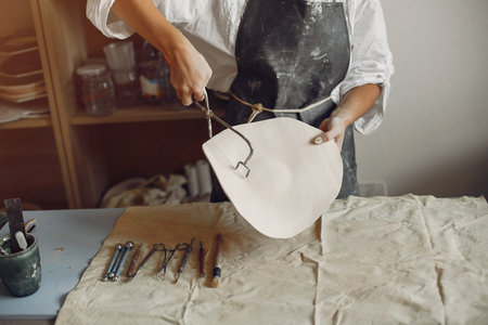 Woman in a pottery. Master make a dishes. Artist works with a clay