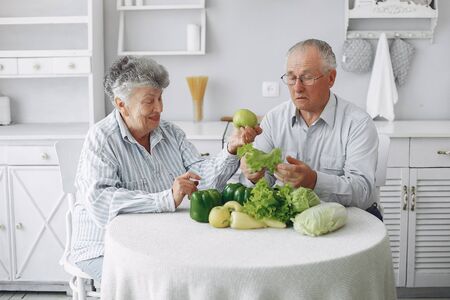 Beautiful old couple prepare food in a kitchenの写真素材