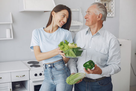 Old man in a kitchen with young granddaughterの写真素材