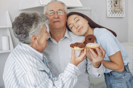 Old couple in a kitchen with young granddaughterの写真素材