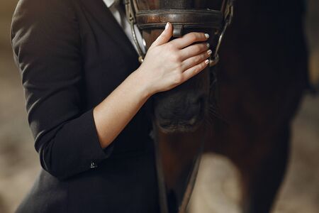 Woman near horse. Rider in a black uniformの写真素材