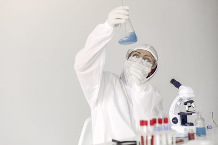 A laboratory scientist is examining blue solution in a bottle
