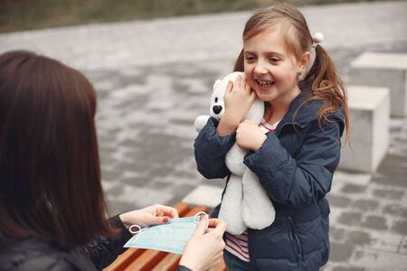 Woman in a disposable mask is teaching her child to wear a respiratorの写真素材