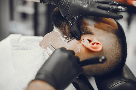 A man in a barbershop. Clipping beard in the barber. Rest in hairdressing salonの写真素材