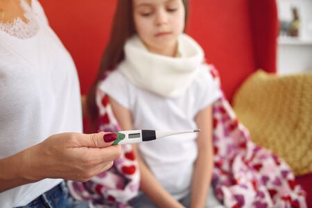 Mom measures the temperature of her ailing daughterの写真素材