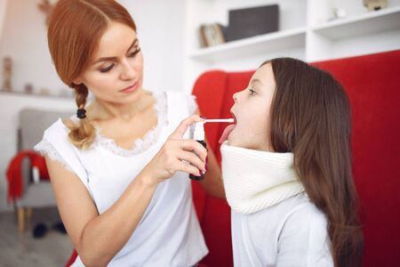 Mother gives her sick daughter throat medicineの写真素材