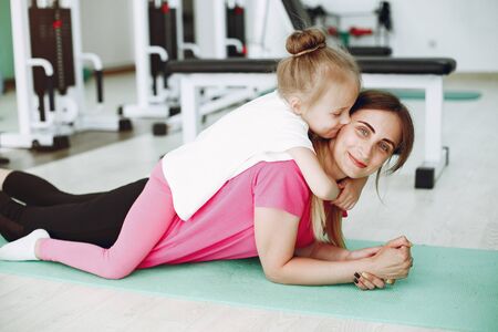 Mother with little daughter are engaged in gymnastics in the gymの写真素材