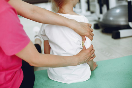 Mother with daughter in a gym. Little girl are engaged in gymnastics