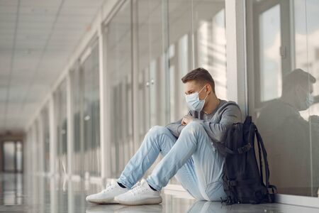 Man in a mask sitting in the hall of hospitalの写真素材