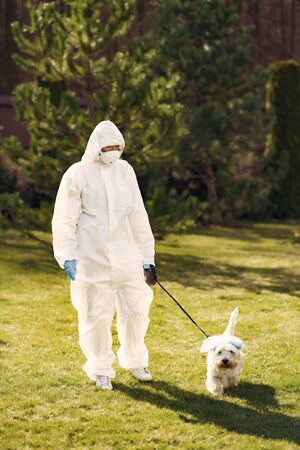 Woman in a protective suit walking with a dogの写真素材