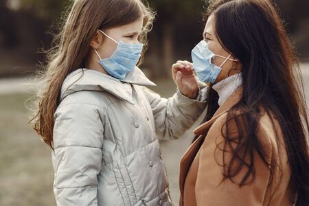 Mother with daughter walks outside in masksの写真素材