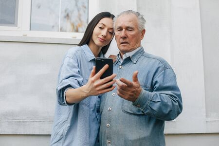 Girl teaching her grandfather how to use a phoneの写真素材