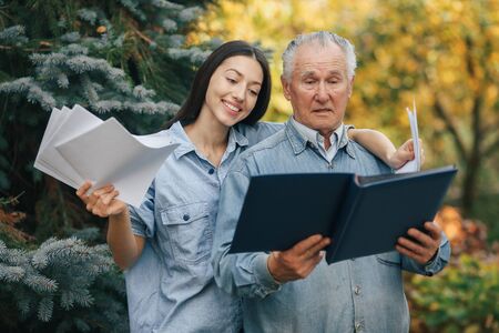 Old man standing in a park backround with his granddaughterの写真素材