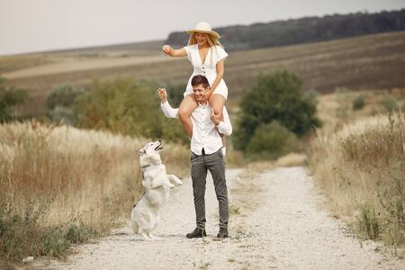 Couple in a autumn field playing with a dogの写真素材