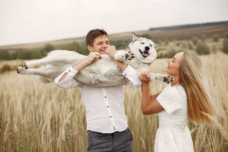 Couple in a autumn field playing with a dogの写真素材