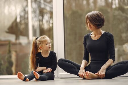 Woman with daughter is engaged in gymnasticsの写真素材