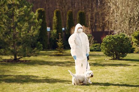 Woman in a protective suit walking with a dogの写真素材