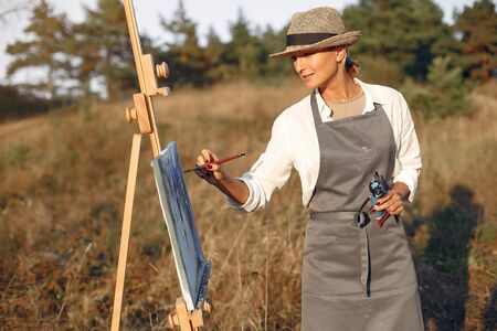 Woman in a apron painting in a fieldの写真素材