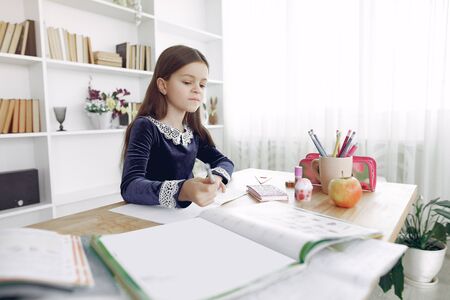 Little girl sitting on a table with booksの写真素材